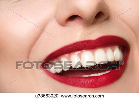 Stock Image - Cropped studio portrait of young woman's smiling mouth. Fotosearch