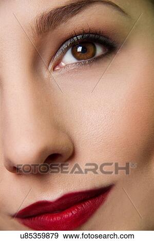 Stock Photo - Cropped studio portrait of young woman's eye and lips. Fotosearch
