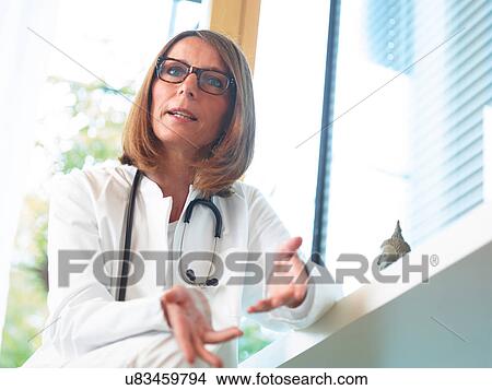 Picture - Doctor sitting at desk in office. Fotosearch