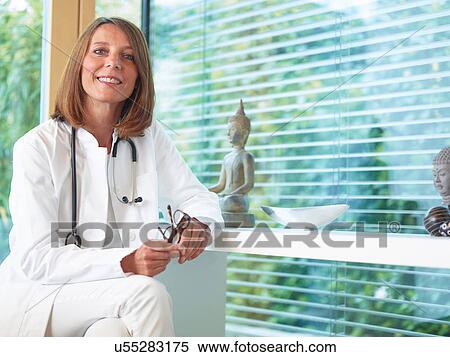 Stock Photography - Doctor sitting at desk in office. Fotosearch