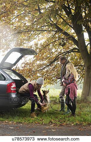 Stock Image - Family and dog preparing for walk from car boot, Norfolk, UK. Fotosearch