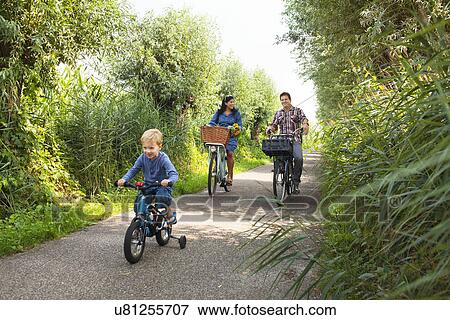 Stock Photo - Family cycling down country lane. Fotosearch