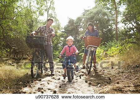 Family cycling though forest View Large Photo Image Stock Photo - Family cycling though forest. Fotosearch