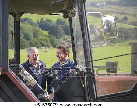 Farmer and son talking next to tractor in field View Large Photo Image Stock Photo - Farmer and son talking next to tractor in field. Fotosearch
