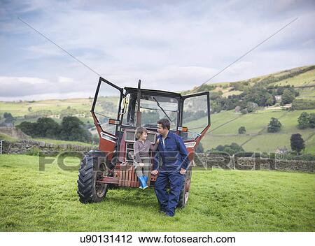 Farmer and young son sitting on tractor in field View Large Photo Image Stock Image - Farmer and young son sitting on tractor in field. Fotosearch