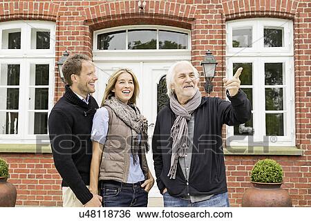 Stock Photograph - Father and mid adult couple outside house. Fotosearch