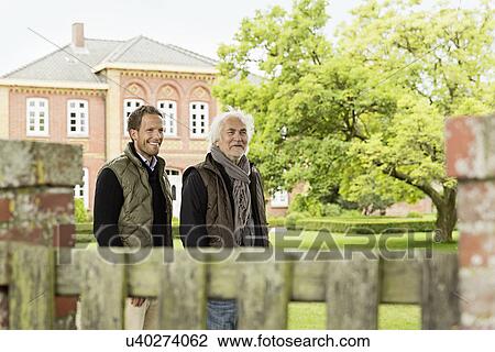 Father and son in garden with house in background View Large Photo Image Stock Image - Father and son in garden with house in background. Fotosearch