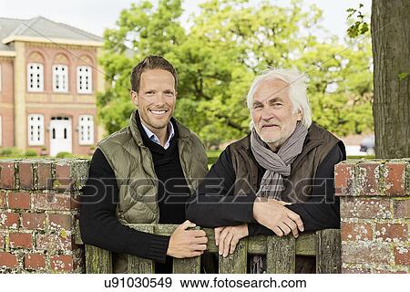 Stock Photo - Father and son leaning on wooden gate. Fotosearch