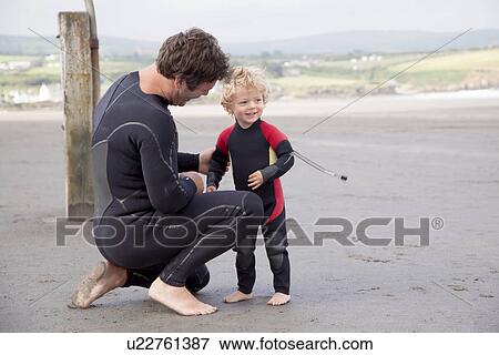 Father and son on beach wearing wet suits View Large Photo Image Stock Photo - Father and son on beach wearing wet suits. Fotosearch