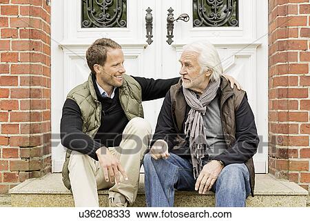 Stock Image - Father and son sitting on doorstep. Fotosearch