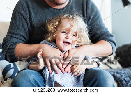 Stock Image - Father holding and tickling toddler son. Fotosearch