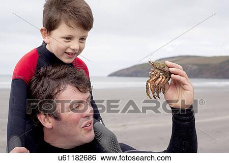 Stock Photograph - Father holding crab with son. Fotosearch
