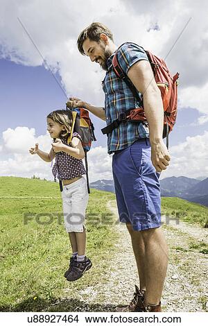 Picture - Father lifting daughter by backpack, Tyrol, Austria. Fotosearch