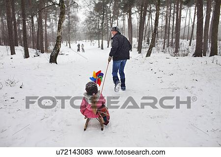 Father pulling daughter on toboggan in snow View Large Photo Image Stock Image - Father pulling daughter on toboggan in snow. Fotosearch