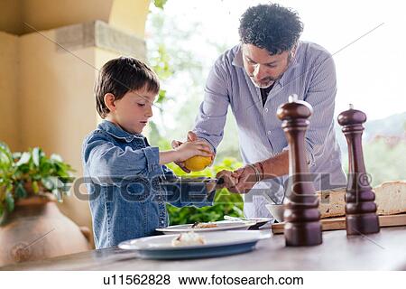 Stock Photo - Father showing son how to grate lemon zest. Fotosearch