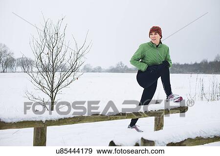 Female jogger stretching before run in snow covered scene View Large Photo Image Stock Photo - Female jogger stretching before run in snow covered scene. Fotosearch