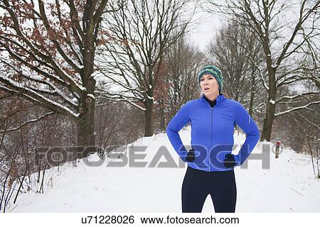 Female jogger taking a break in snow covered scene View Large Photo Image Stock Photograph - Female jogger taking a break in snow covered scene. Fotosearch
