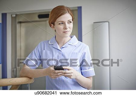 Female nurse with mobile phone outside hospital lift View Large Photo Image Stock Image - Female nurse with mobile phone outside hospital lift. Fotosearch