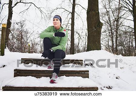 Stock Photo - Female runner relaxing on snow covered staircase in winter. Fotosearch