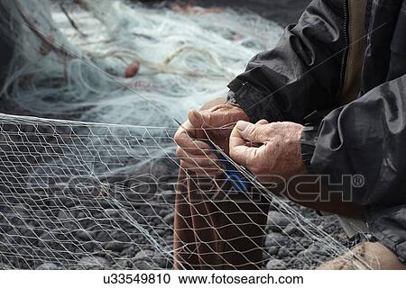 Fisherman repairing net on pebble beach View Large Photo Image Stock Image - Fisherman repairing net on pebble beach. Fotosearch