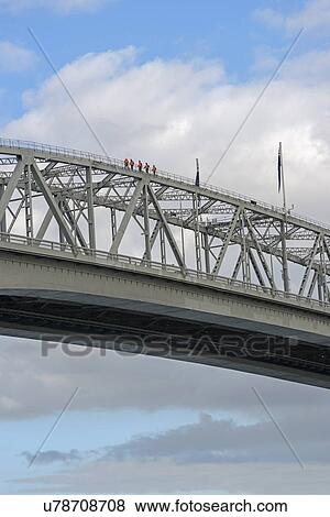 Stock Photo - Five people walking on top of harbor bridge, Auckland, North Island, New Zealand. Fotosearch