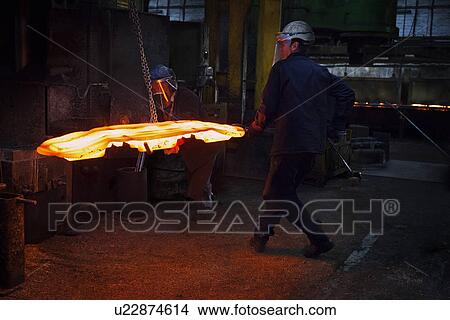 Picture - Flight bar (mining component) having been forged in a 15 MT counterblow hammer, is moved to clipping press to clip off excess "flash". Fotosearch