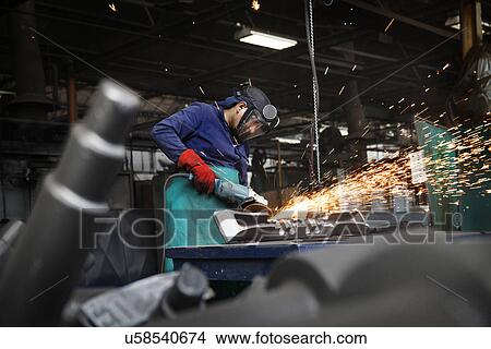 Picture - Forge worker grinding (or linishing) flight bar (mining component), removing last traces of excess "flash" not removed by clipping press. Fotosearch