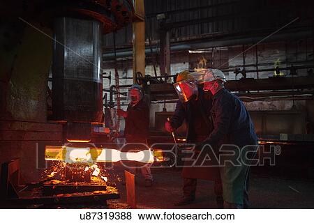 Forge workers pre form red hot steel billet into flight bar (mining component) on hammer View Large Photo Image Stock Photo - Forge workers pre form red hot steel billet into flight bar (mining component) on hammer. Fotosearch