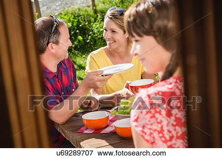 Stock Photo - Friends breakfasting at table outside chalet, Tyrol, Austria. Fotosearch