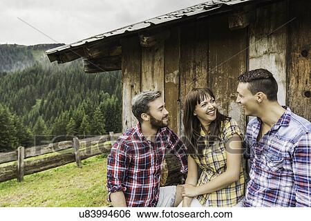 Friends chatting behind wooden shack, Tirol, Austria View Large Photo Image Stock Photograph - Friends chatting behind wooden shack, Tirol, Austria. Fotosearch