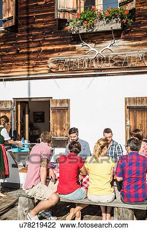 Stock Image - Friends having breakfast outside chalet, Tyrol, Austria. Fotosearch