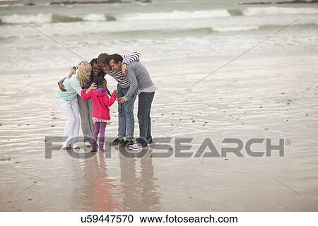 Stock Image - Friends sharing secret with child on beach. Fotosearch