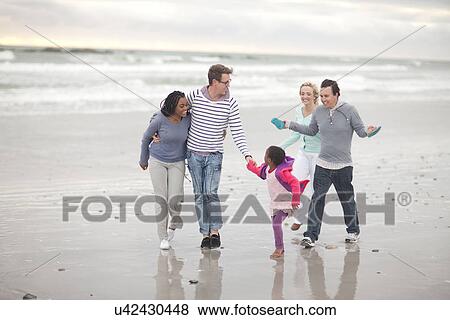 Stock Photo - Friends with child walking on beach. Fotosearch