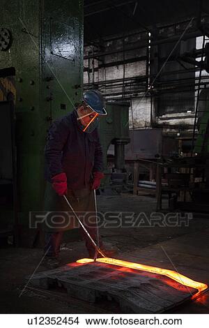 Fully forged and clipped flight bar (mining component) is lined up to cool down for final stage of finishing process View Large Photo Image Picture - Fully forged and clipped flight bar (mining component) is lined up to cool down for final stage of finishing process. Fotosearch