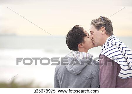 Stock Photography - Gay couple kissing on beach. Fotosearch