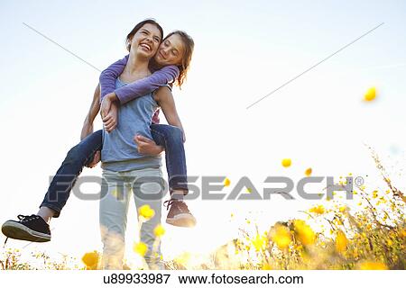 Stock Photo - Girl giving sister piggy back. Fotosearch