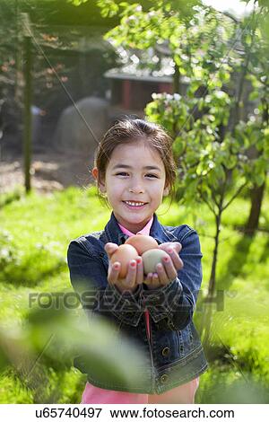 Stock Photo - Girl holding eggs in garden. Fotosearch