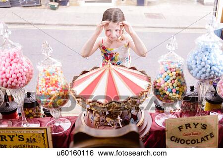 Girl looking through window of sweet shop View Large Photo Image Stock Photograph - Girl looking through window of sweet shop. Fotosearch