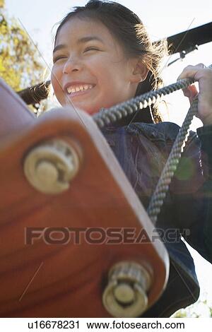 Stock Image - Girl on swing, low angle. Fotosearch