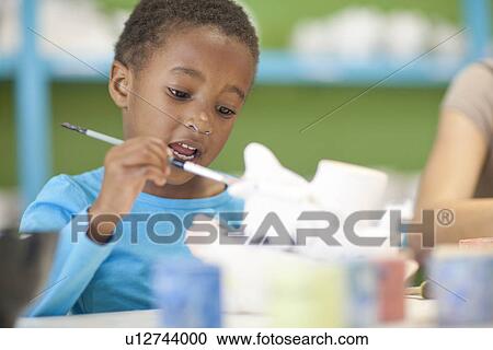 Stock Image - Girl painting in art class. Fotosearch