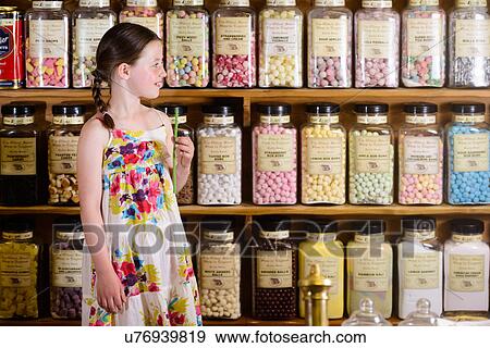 Girl standing in sweet shop in front of shelves of confectionery View Large Photo Image Stock Photo - Girl standing in sweet shop in front of shelves of confectionery. Fotosearch