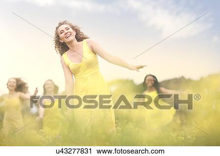 Girls in yellow dancing on meadow View Large Photo Image Stock Image - Girls in yellow dancing on meadow. Fotosearch