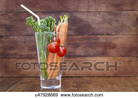 Stock Photo - Glass of broccoli, carrots and tomato with straw. Fotosearch
