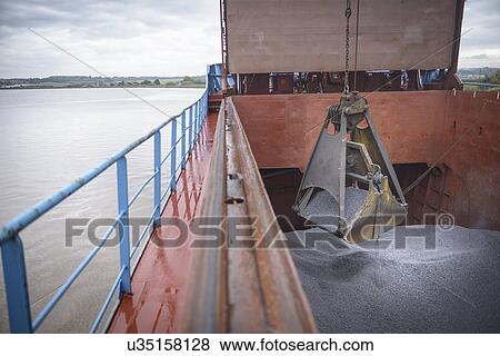 Stock Photo - Grab unloading metal alloy from ship's hull. Fotosearch