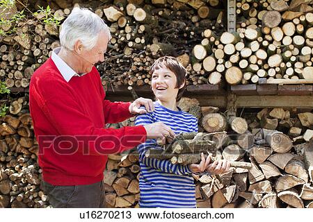 Stock Image - Grandfather and grandson with logs. Fotosearch