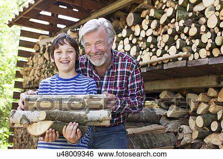 Grandfather and grandson with logs View Large Photo Image Stock Photograph - Grandfather and grandson with logs. Fotosearch