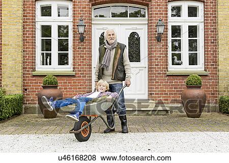 Grandfather pushing grandson in wheelbarrow View Large Photo Image Stock Photo - Grandfather pushing grandson in wheelbarrow. Fotosearch
