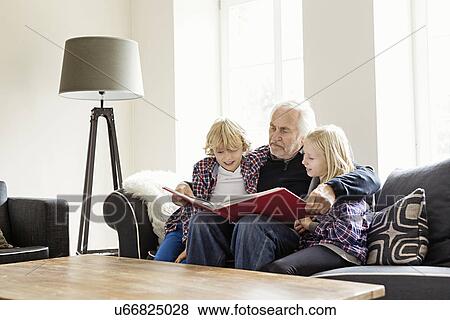 Stock Photo - Grandfather reading book to grandchildren. Fotosearch