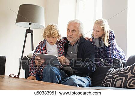 Grandfather using digital tablet with grandchildren View Large Photo Image Stock Image - Grandfather using digital tablet with grandchildren. Fotosearch