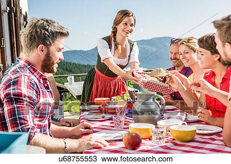 Stock Image - Group of friends at breakfast outside chalet, Tyrol, Austria. Fotosearch